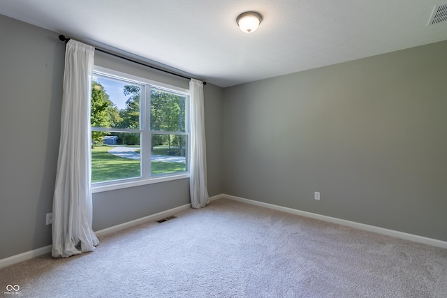 unfurnished room with visible vents, light carpet, and baseboards