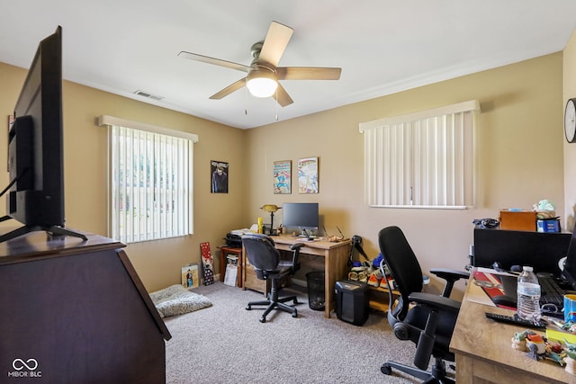 carpeted home office with ceiling fan and visible vents