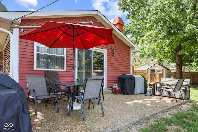 view of patio / terrace with a storage shed, area for grilling, an outbuilding, fence, and outdoor dining area