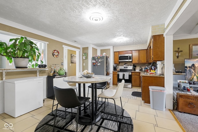 tiled dining area with a textured ceiling and crown molding