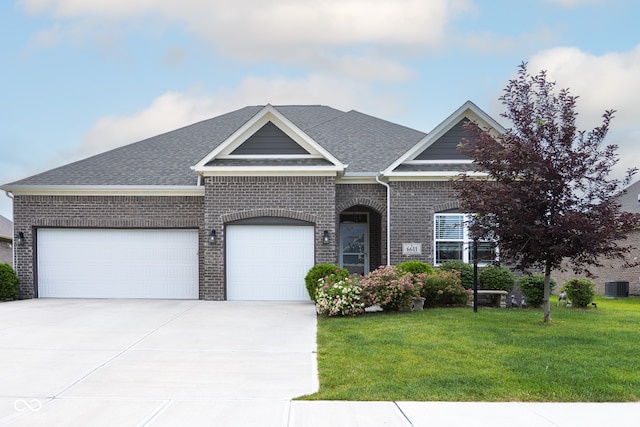 view of front of property featuring a garage, a front yard, and central AC