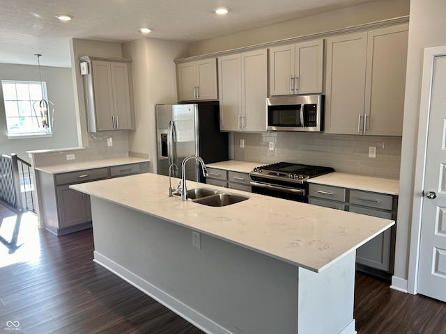 kitchen featuring decorative backsplash, appliances with stainless steel finishes, light stone counters, sink, and gray cabinets