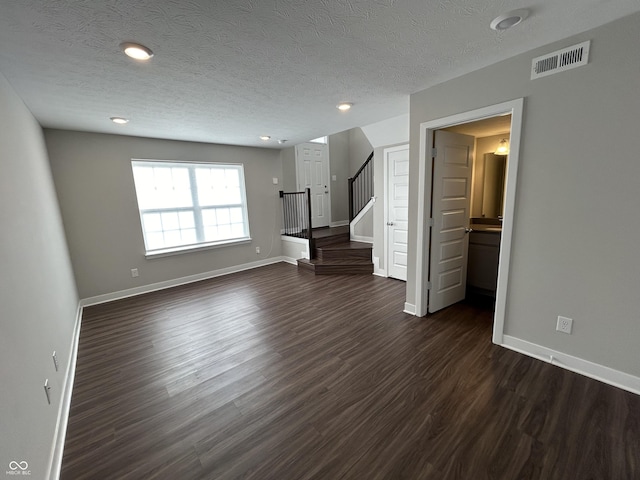 unfurnished living room featuring dark wood-type flooring and a textured ceiling