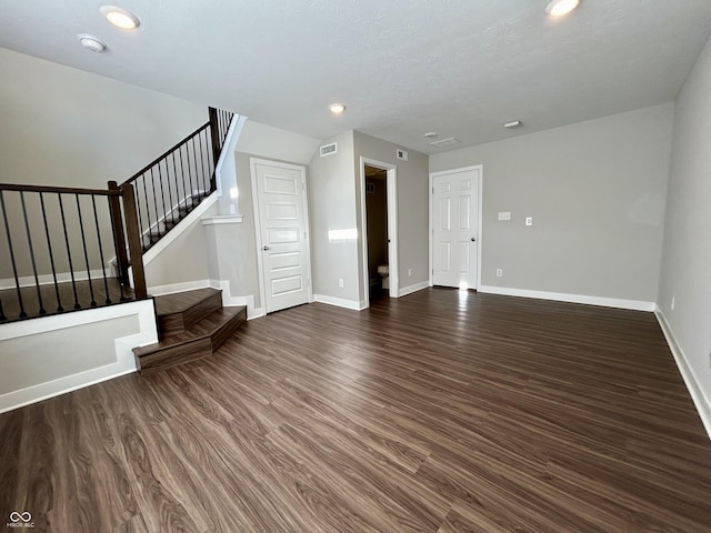 unfurnished living room with a textured ceiling and dark hardwood / wood-style floors