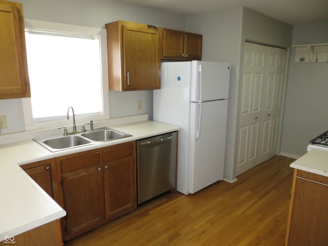 kitchen featuring light wood-type flooring, white appliances, and sink