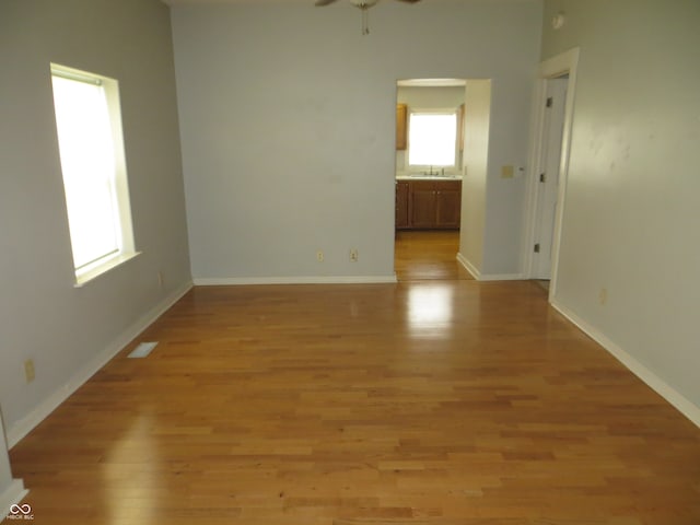 empty room featuring light wood-type flooring, a wealth of natural light, sink, and ceiling fan