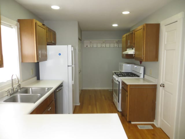 kitchen featuring hardwood / wood-style flooring, white gas range, dishwasher, and sink