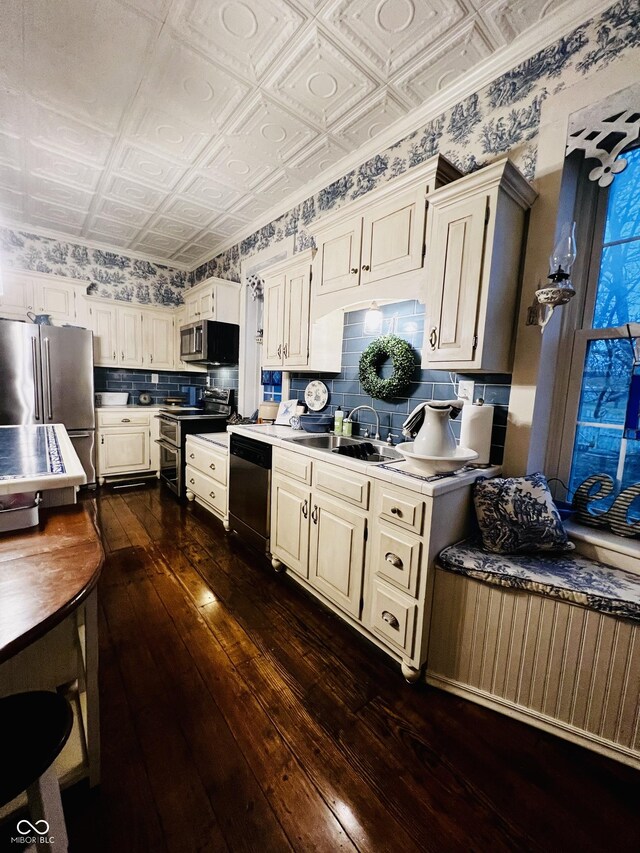 kitchen with a sink, an ornate ceiling, tasteful backsplash, and appliances with stainless steel finishes