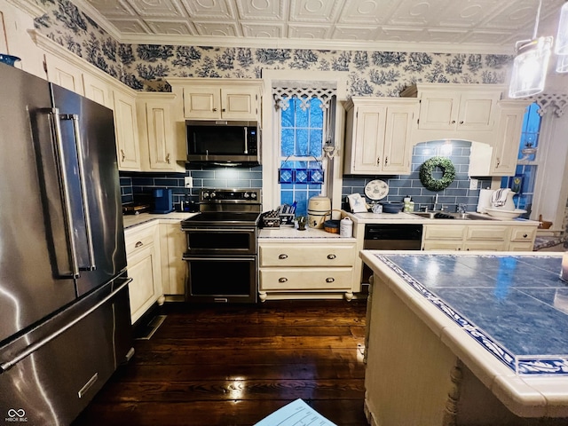 kitchen with a sink, an ornate ceiling, appliances with stainless steel finishes, and dark wood-style floors