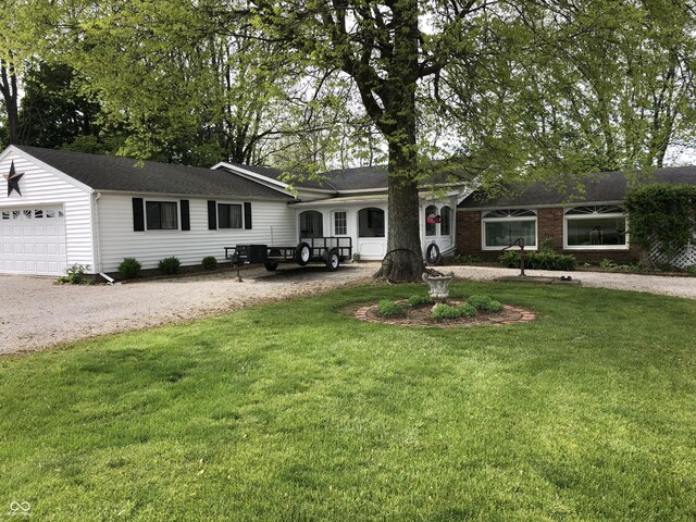 single story home featuring brick siding, a garage, gravel driveway, and a front lawn