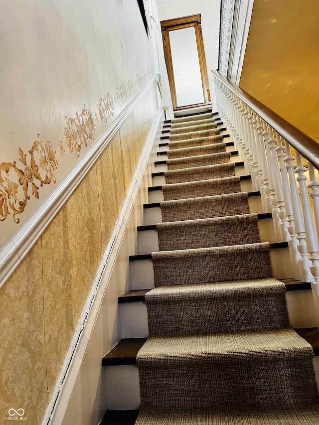 staircase with a decorative wall and wainscoting