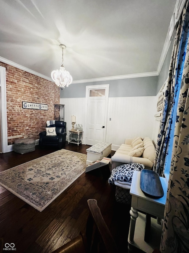 living room featuring wood finished floors, an inviting chandelier, brick wall, wainscoting, and crown molding