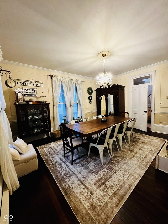 dining room with an inviting chandelier, a decorative wall, wood finished floors, and ornamental molding