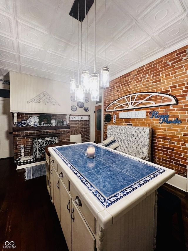 kitchen featuring an ornate ceiling, brick wall, and dark wood-type flooring