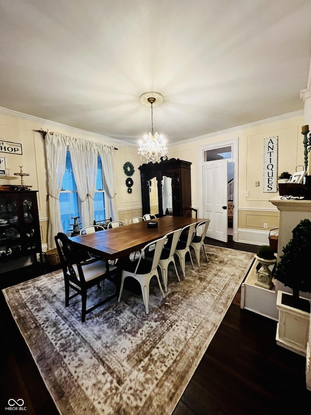 dining space with dark wood-style floors, a decorative wall, ornamental molding, and a chandelier