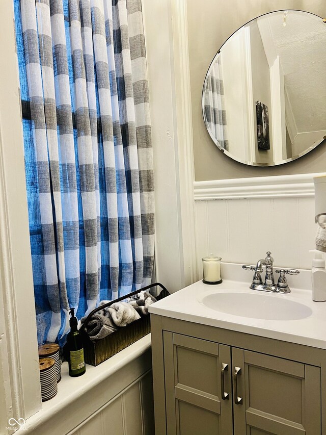 bathroom featuring a wainscoted wall, vanity, and a decorative wall