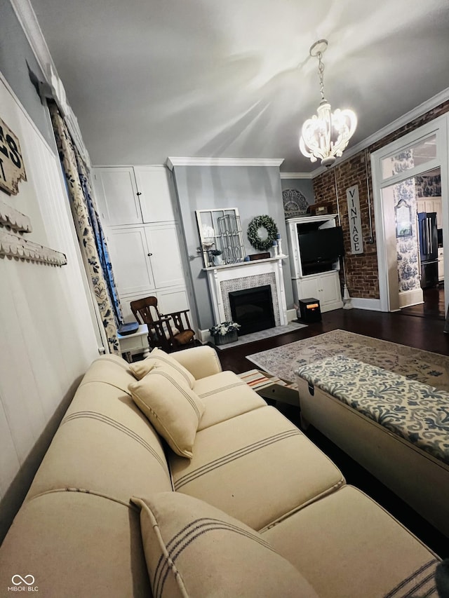 living area with brick wall, a fireplace, dark wood-type flooring, crown molding, and a notable chandelier