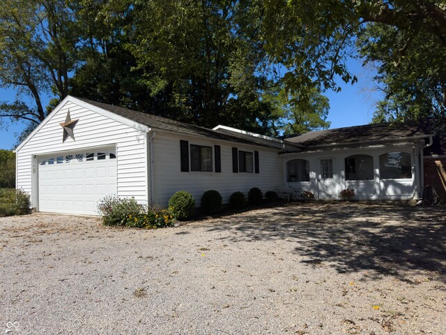 ranch-style house featuring gravel driveway and a garage