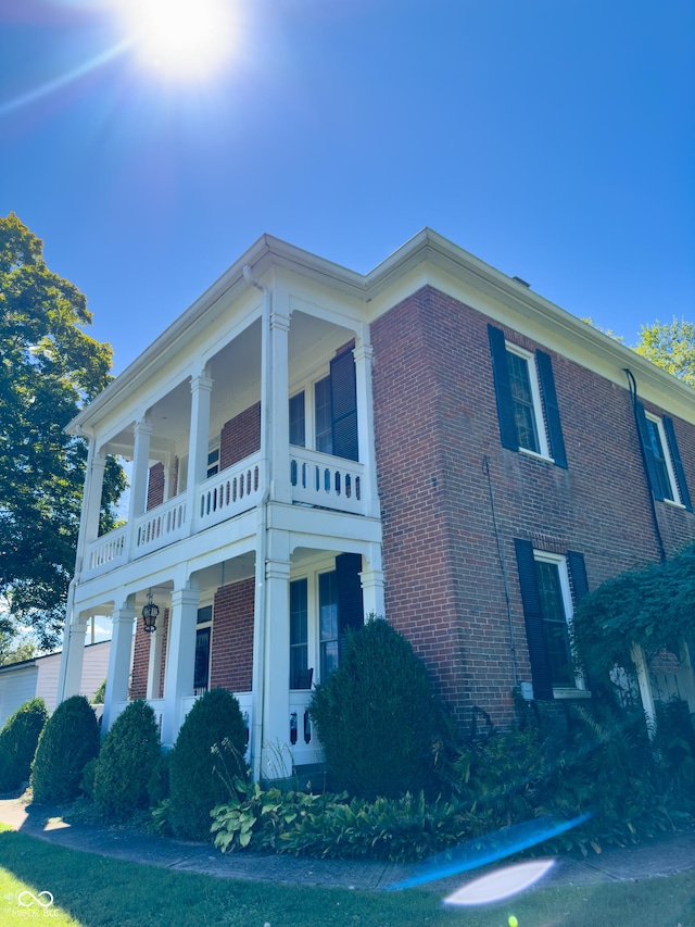 view of side of home with brick siding and a balcony