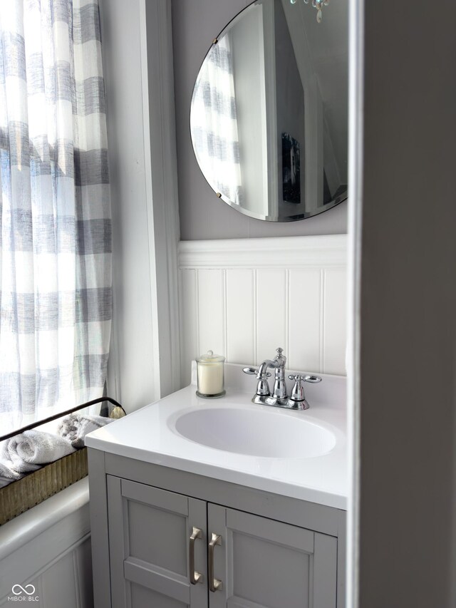 bathroom with a wainscoted wall, vanity, and a decorative wall