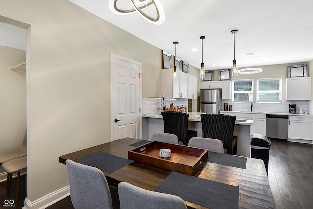 dining space with dark wood-type flooring, a chandelier, and sink