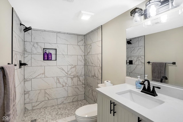 bathroom featuring vanity, toilet, and a tile shower