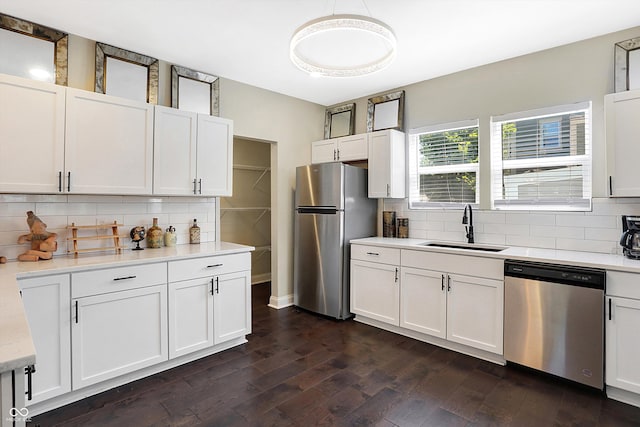 kitchen with appliances with stainless steel finishes, tasteful backsplash, dark wood-type flooring, sink, and white cabinetry