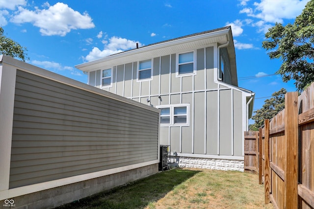 rear view of house featuring a yard, fence, and board and batten siding