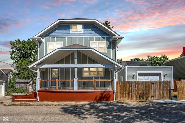 view of front of home with board and batten siding, fence, and covered porch