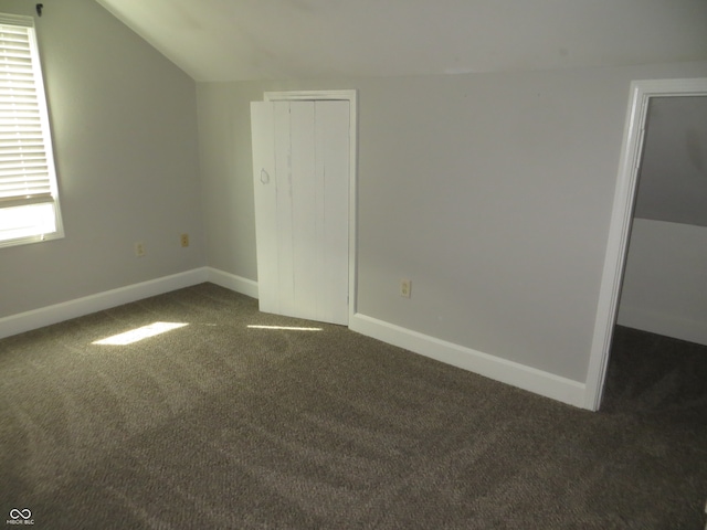 unfurnished bedroom with multiple windows, carpet flooring, a closet, and vaulted ceiling