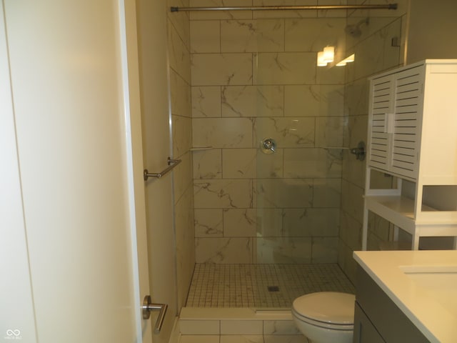 bathroom with vanity, toilet, and a tile shower