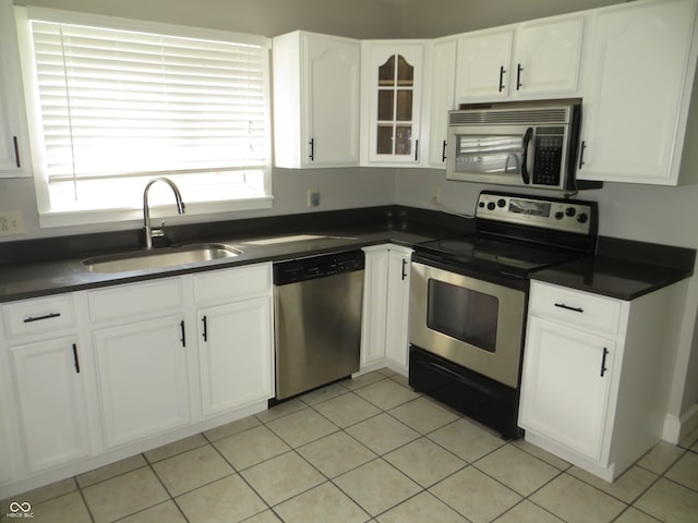 kitchen featuring sink, light tile patterned floors, appliances with stainless steel finishes, and white cabinetry