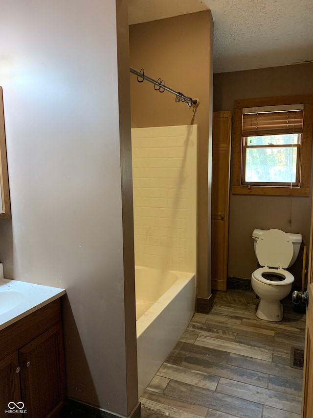 full bathroom featuring hardwood / wood-style flooring, a textured ceiling, vanity, shower / washtub combination, and toilet