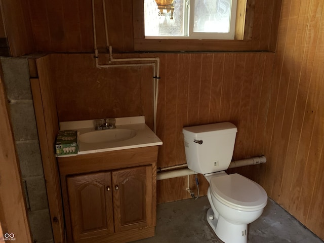 bathroom featuring toilet, vanity, and wooden walls