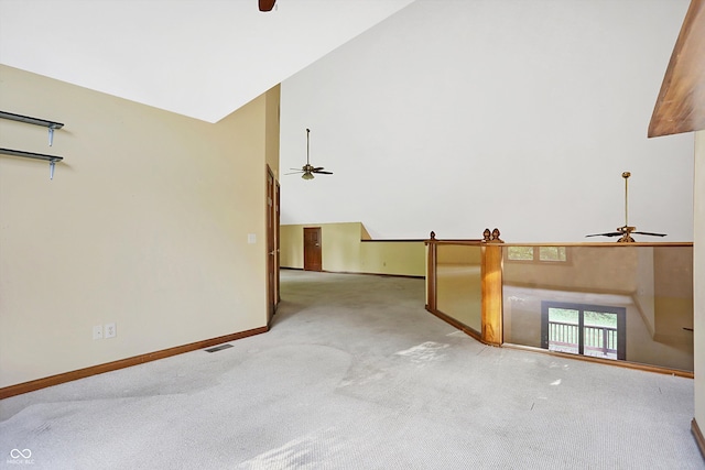 carpeted empty room featuring ceiling fan, a barn door, and high vaulted ceiling