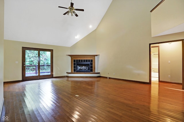 unfurnished living room with ceiling fan, a tile fireplace, wood-type flooring, and high vaulted ceiling