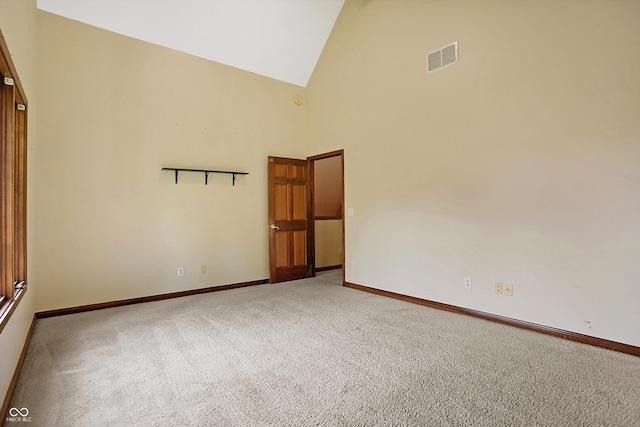 unfurnished room featuring carpet and high vaulted ceiling