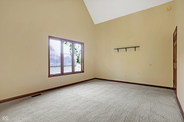 carpeted empty room with high vaulted ceiling