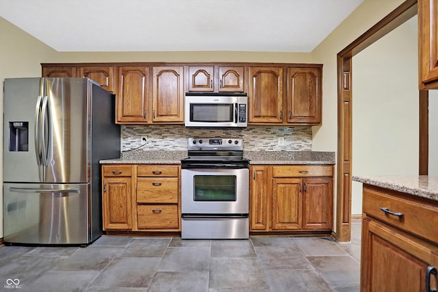 kitchen featuring backsplash, light stone counters, and stainless steel appliances