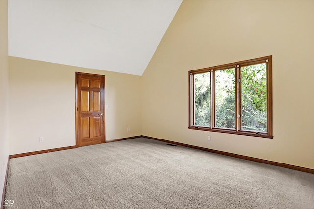 carpeted spare room featuring high vaulted ceiling