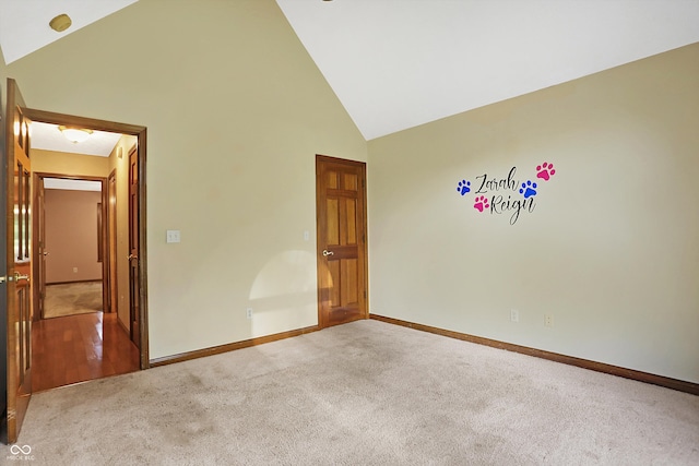 carpeted spare room featuring high vaulted ceiling