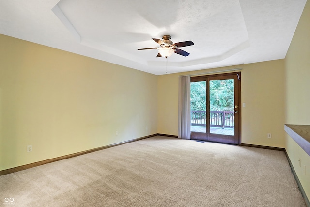 unfurnished room with a tray ceiling, ceiling fan, and light colored carpet