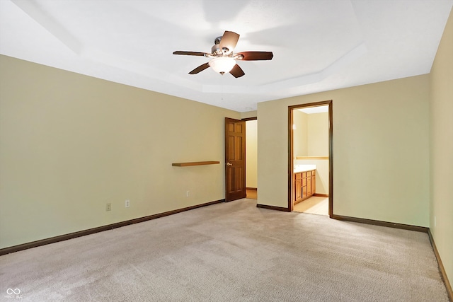 carpeted empty room featuring ceiling fan and a raised ceiling