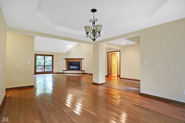 unfurnished living room featuring a tiled fireplace, a chandelier, wood-type flooring, and vaulted ceiling