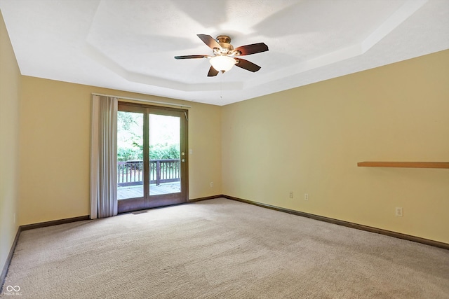 unfurnished room with ceiling fan, carpet floors, and a tray ceiling