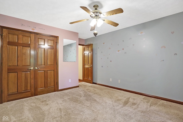 unfurnished bedroom featuring ceiling fan, a closet, and light colored carpet