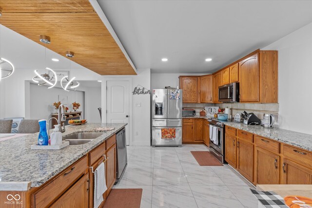 kitchen featuring tasteful backsplash, light stone counters, stainless steel appliances, sink, and pendant lighting