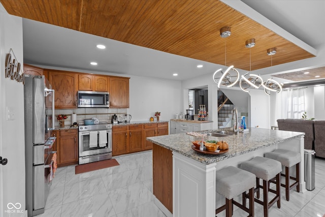 kitchen featuring wooden ceiling, hanging light fixtures, an island with sink, and stainless steel appliances