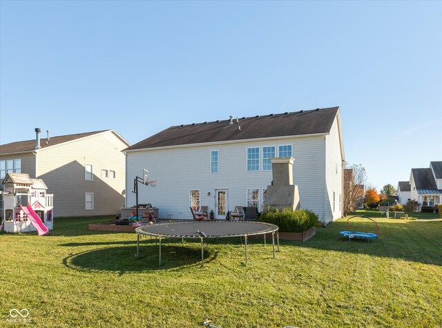 rear view of property featuring a yard and a trampoline