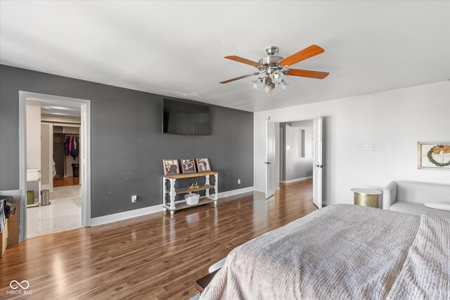 bedroom featuring ceiling fan, dark hardwood / wood-style flooring, and a walk in closet